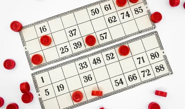 Two bingo cards with red playing chips scattered on them.