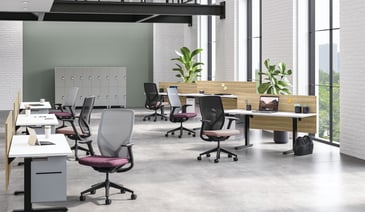 Open-plan office with mesh chairs and standing desks.