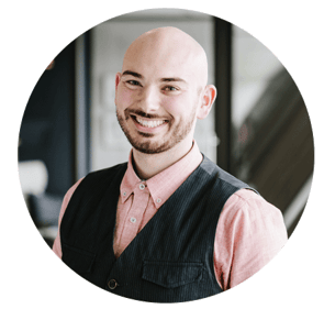 Alex Scott, Designer / Project Planner, smiling in a dark vest and pink shirt.