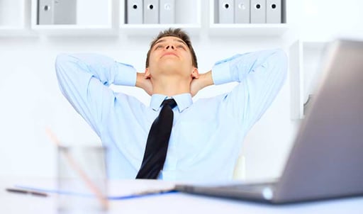 A man relaxing at his desk in an office.