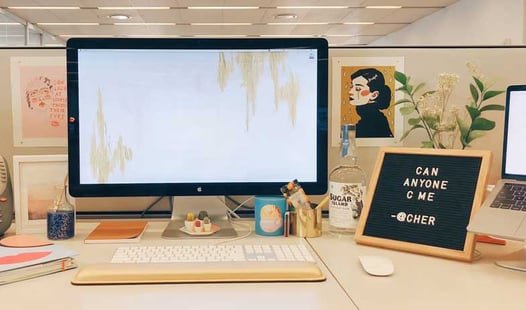 A desktop workstation decorated with personal items, artwork, and a letter board. 