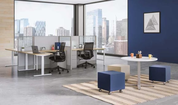 Modern office workspace with desks, chairs, and collaborative seating overlooking a cityscape.