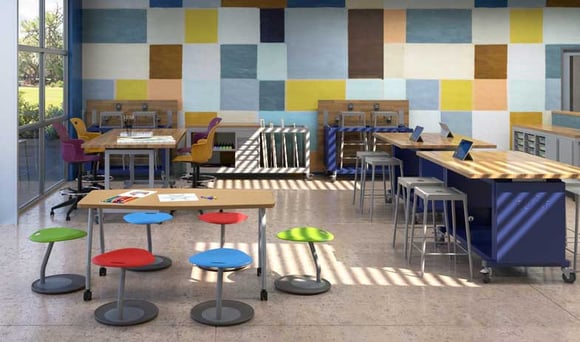 Bright and colorful makerspace classroom with adjustable tables, stools, and workstations.