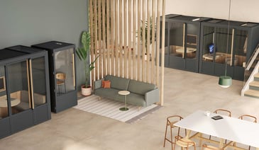 Modern office space with glass-walled meeting pods, a green sofa, wooden slat room divider, and minimalist furniture in neutral tones.